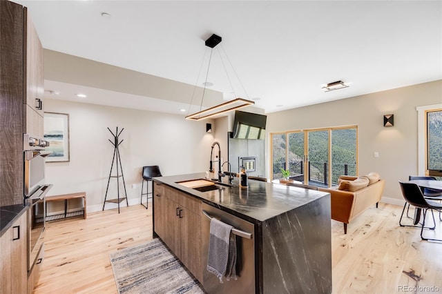 kitchen with light wood-style floors, open floor plan, a sink, and decorative light fixtures