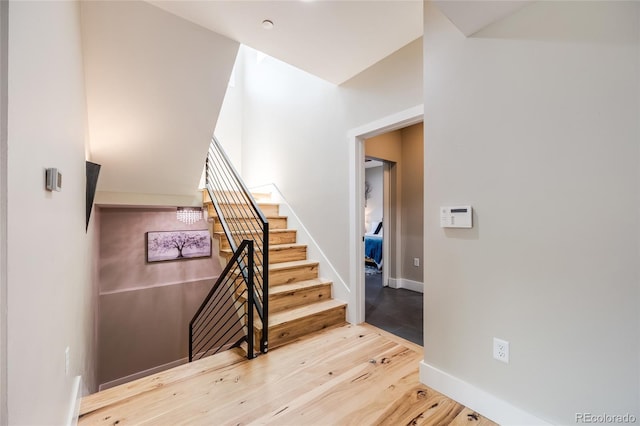 staircase featuring wood finished floors and baseboards