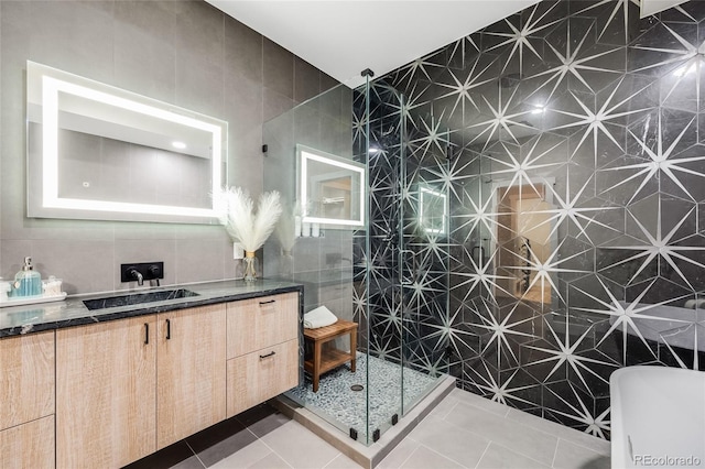 full bathroom featuring tiled shower, vanity, tile walls, and tile patterned floors