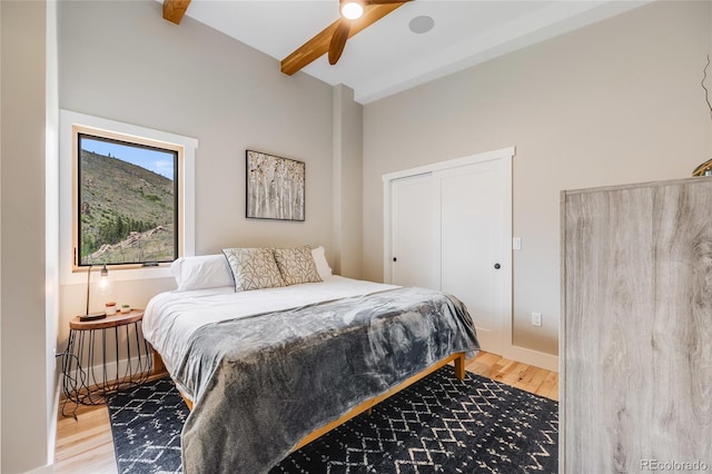 bedroom featuring beam ceiling, ceiling fan, baseboards, and wood finished floors