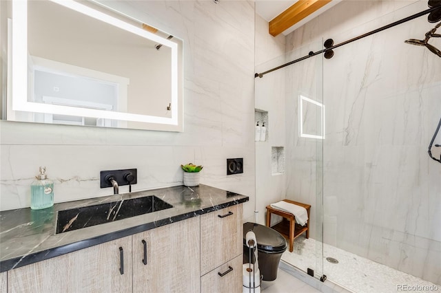 bathroom with toilet, a marble finish shower, tile walls, and vanity