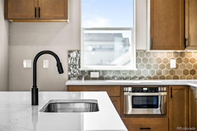 16605 Peak St, Broomfield, CO 80023 - kitchen featuring stainless steel oven, light countertops, backsplash, and brown cabinets