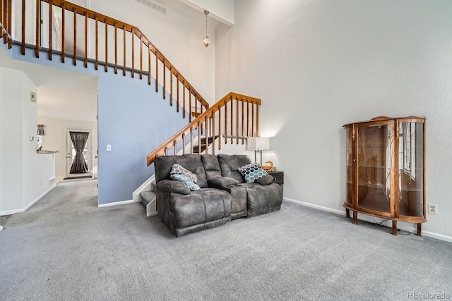 carpeted living room featuring a towering ceiling