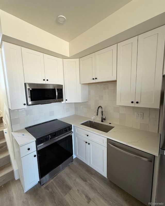 kitchen with appliances with stainless steel finishes, sink, hardwood / wood-style floors, and white cabinets