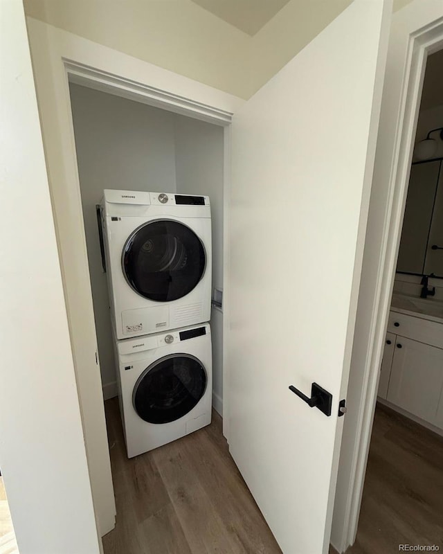 laundry room featuring light hardwood / wood-style floors and stacked washer / dryer