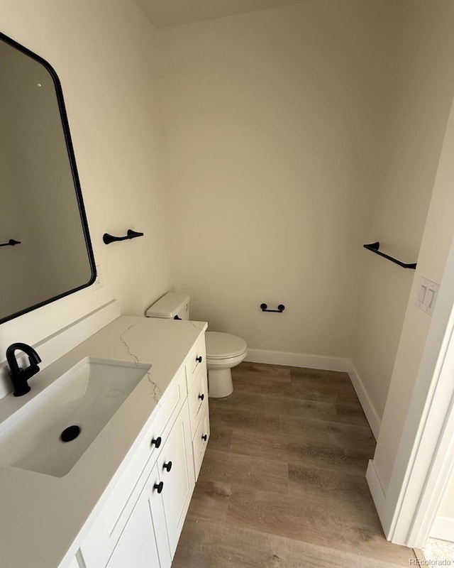 bathroom featuring wood-type flooring, toilet, and vanity