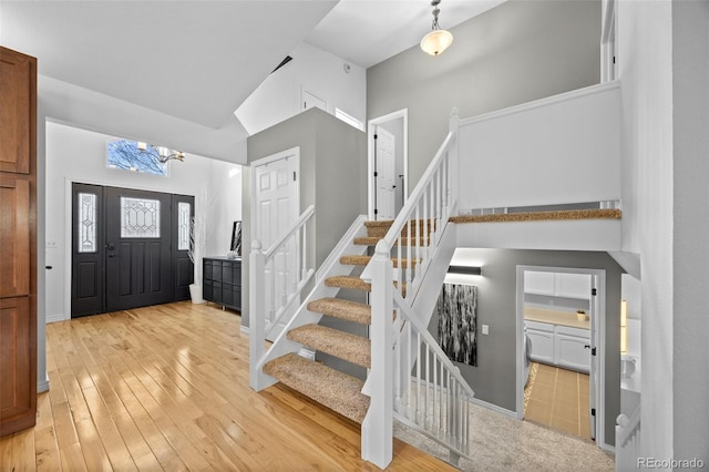 entrance foyer with high vaulted ceiling and light hardwood / wood-style flooring