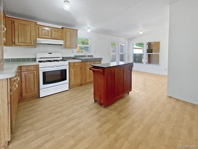 kitchen featuring gas range gas stove, sink, light hardwood / wood-style flooring, lofted ceiling, and a kitchen island