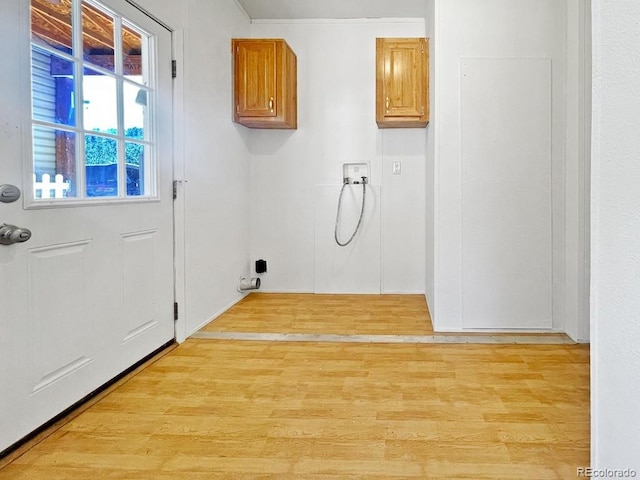 washroom with washer hookup, light hardwood / wood-style floors, and cabinets