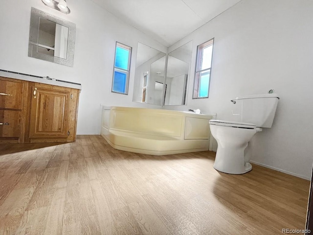 bathroom featuring a washtub, toilet, and wood-type flooring