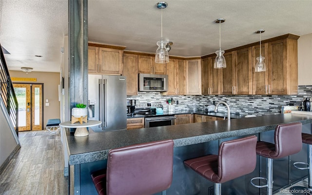 134 Ensign Dr Unit A, Dillon, CO 80435 - kitchen with stainless steel appliances, dark countertops, a textured ceiling, brown cabinets, and decorative backsplash