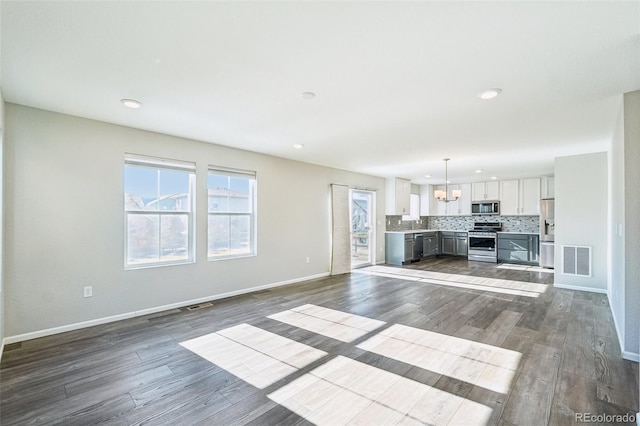 unfurnished living room with dark wood-type flooring and a notable chandelier