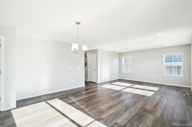 unfurnished room featuring a chandelier and dark wood-type flooring