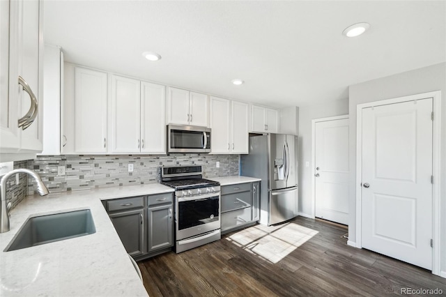 kitchen featuring gray cabinetry, sink, dark hardwood / wood-style floors, white cabinets, and appliances with stainless steel finishes