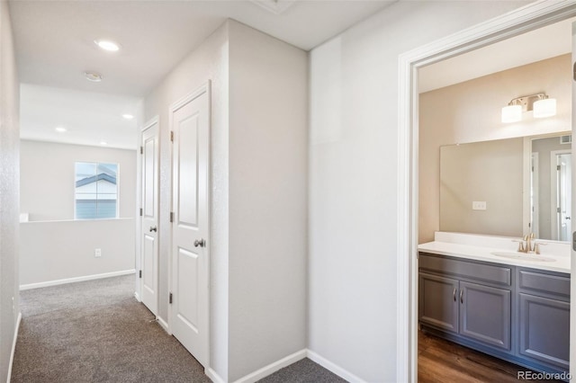 hallway with sink and dark colored carpet