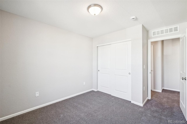 unfurnished bedroom featuring dark colored carpet and a closet