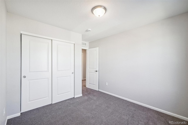 unfurnished bedroom featuring dark colored carpet and a closet