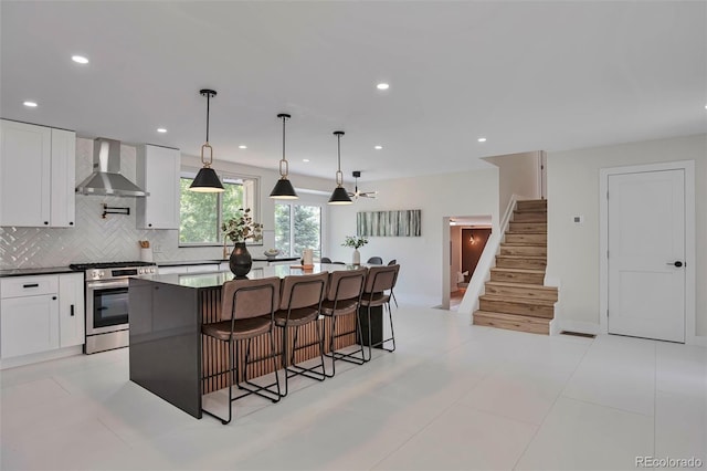7684 S Ingalls St, Littleton, CO 80128 - kitchen featuring stainless steel gas range, wall chimney range hood, backsplash, white cabinetry, and recessed lighting