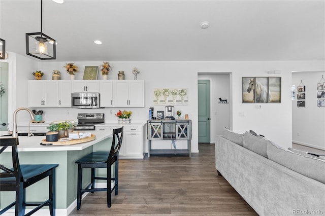 kitchen featuring sink, dark wood-type flooring, stainless steel appliances, a breakfast bar area, and white cabinets