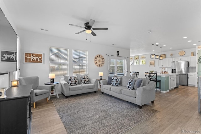 living room featuring light hardwood / wood-style floors, ceiling fan, and sink