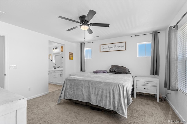 carpeted bedroom with multiple windows, ceiling fan, sink, and ensuite bath