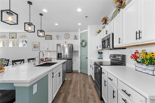 kitchen with a breakfast bar, a center island with sink, sink, appliances with stainless steel finishes, and white cabinetry