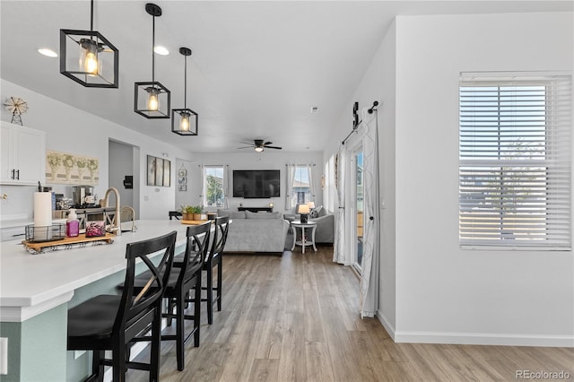 dining space featuring a barn door, ceiling fan, sink, and light hardwood / wood-style floors