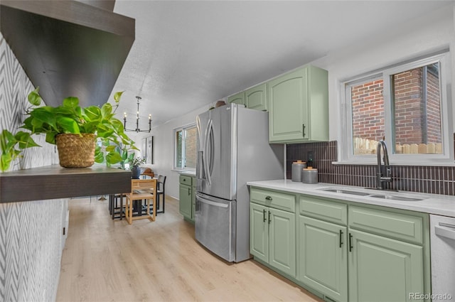 kitchen with a sink, light countertops, appliances with stainless steel finishes, light wood-style floors, and green cabinets