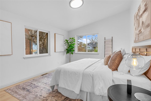 bedroom with wood finished floors and lofted ceiling