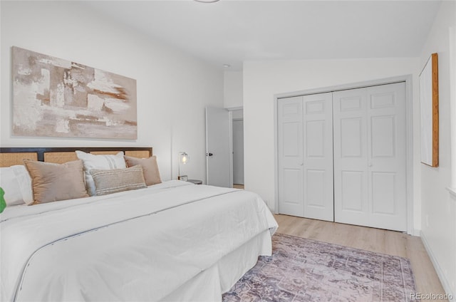 bedroom with a closet, light wood finished floors, and vaulted ceiling