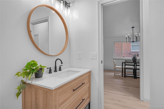 bathroom featuring a notable chandelier, wood finished floors, and vanity