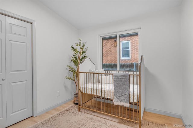 unfurnished bedroom featuring baseboards, vaulted ceiling, a crib, and wood finished floors
