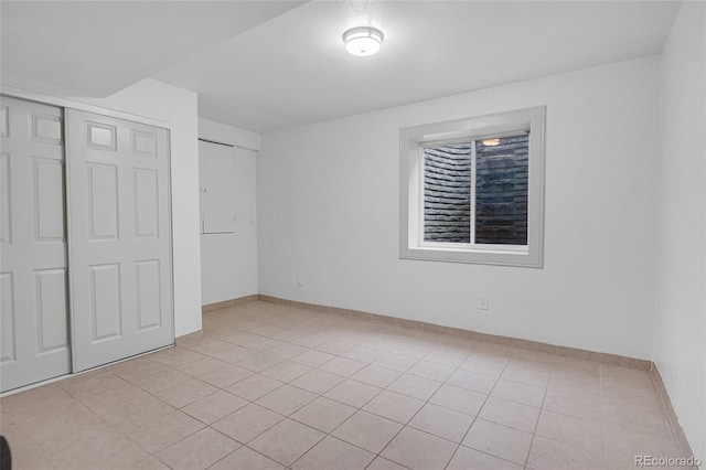 unfurnished bedroom with light tile patterned floors, baseboards, and a closet