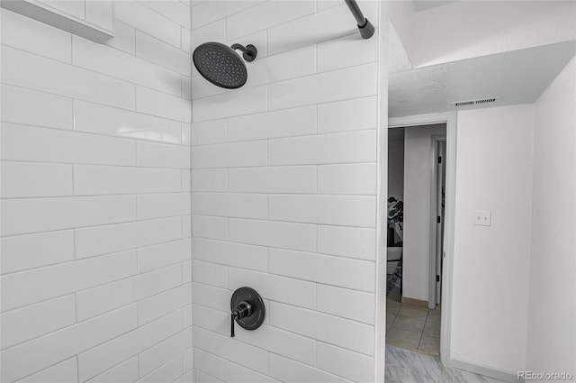 bathroom with visible vents and a tile shower