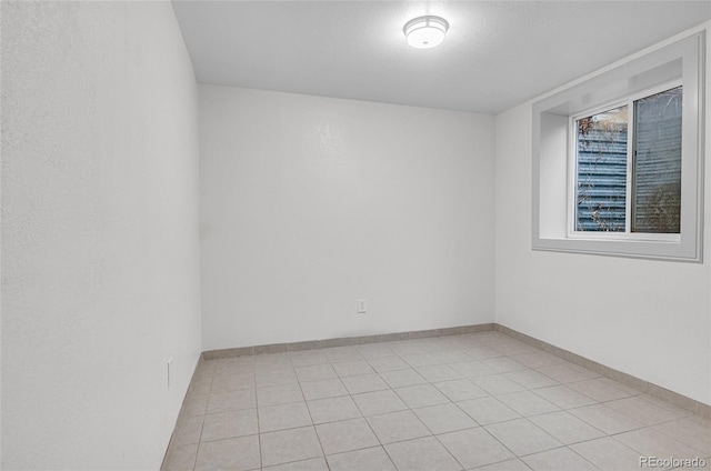 empty room featuring light tile patterned flooring and baseboards