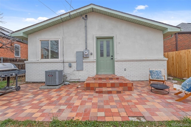 rear view of property featuring central AC, fence, and brick siding
