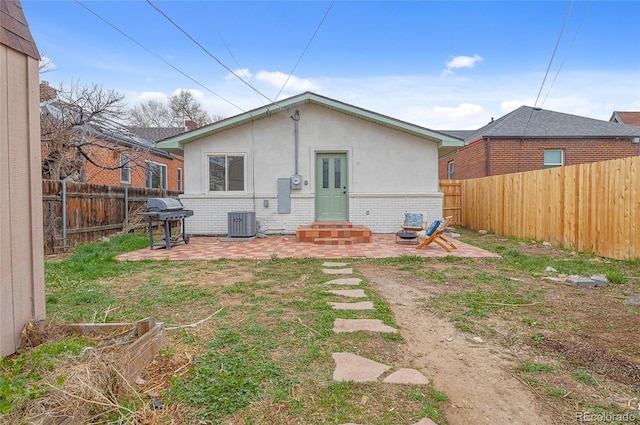 back of property with a fenced backyard, stucco siding, a patio area, brick siding, and central AC unit