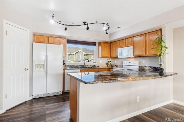 kitchen featuring a peninsula, white appliances, dark stone counters, and dark wood-style flooring