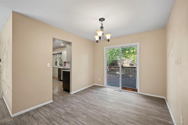 spare room featuring wood-type flooring and an inviting chandelier