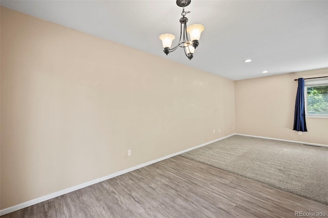 unfurnished room with hardwood / wood-style floors and a chandelier