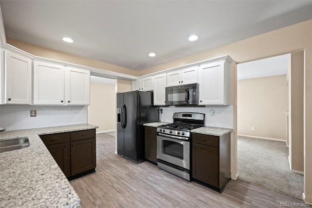 kitchen with light hardwood / wood-style flooring, white cabinets, and black appliances