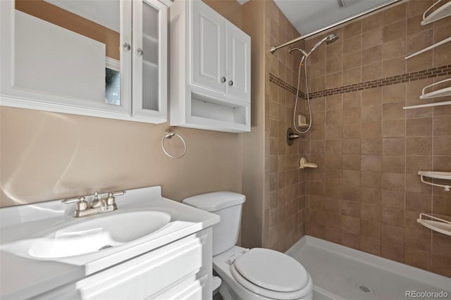 bathroom featuring tiled shower, vanity, and toilet