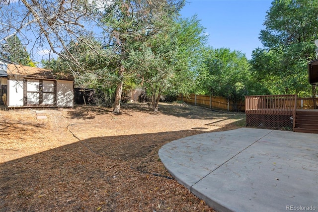 view of yard featuring a deck, a storage shed, and a patio area