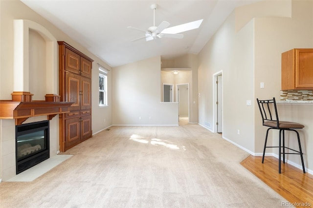 living room with ceiling fan, light colored carpet, and lofted ceiling with skylight