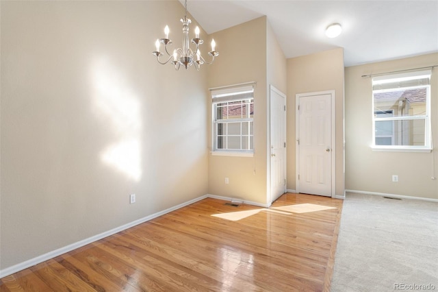 empty room featuring a notable chandelier and light hardwood / wood-style flooring