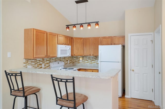 kitchen with light hardwood / wood-style floors, kitchen peninsula, white appliances, and high vaulted ceiling