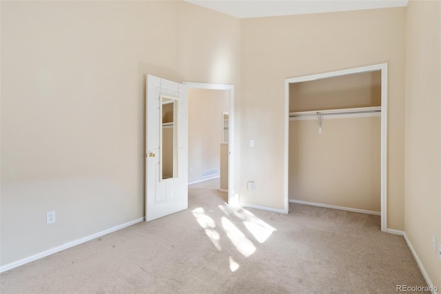 unfurnished bedroom featuring light carpet and a closet