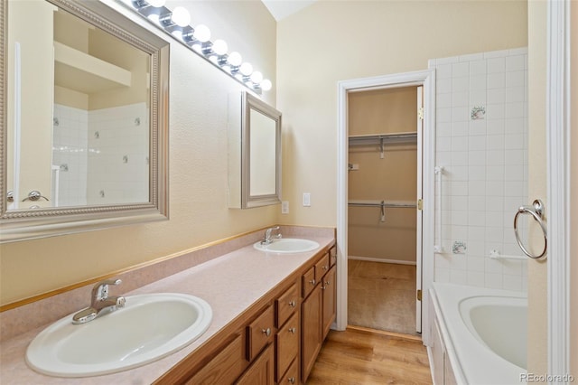 bathroom featuring wood-type flooring, a washtub, and vanity