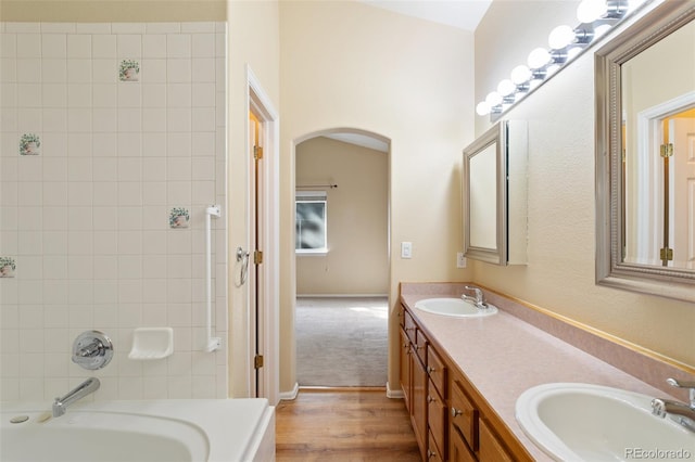 bathroom featuring lofted ceiling, a bath, hardwood / wood-style flooring, and vanity