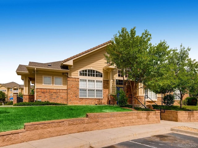 5705 N Genoa Way Unit 308, Aurora, CO 80019 - view of front of home with brick siding, uncovered parking, a front lawn, and a tiled roof